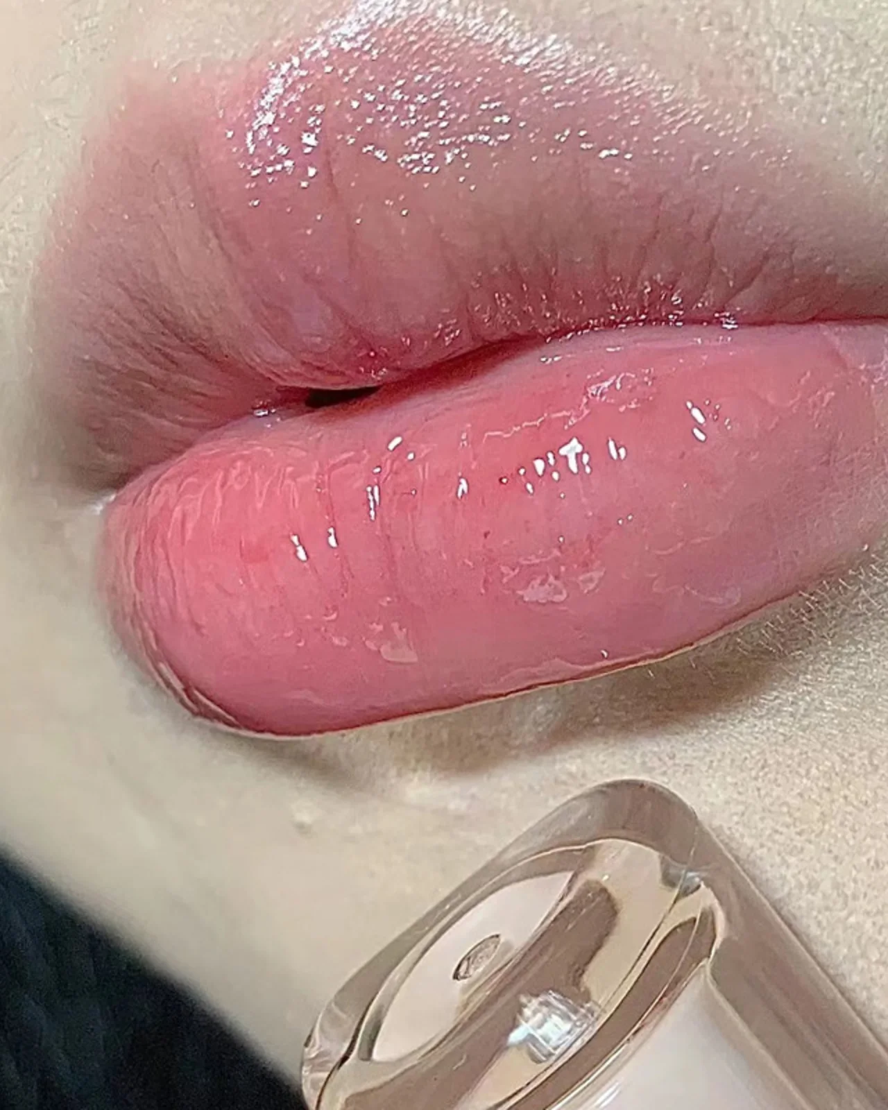 A sheer pink glassy lip tint worn on the lips