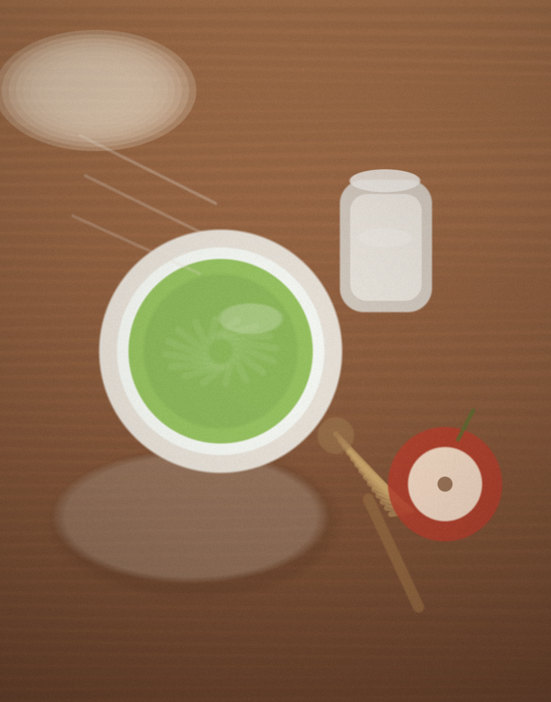A top-down still life of a bowl of whisked matcha on a warm wooden table with a bamboo whisk, a small silver milk pitcher, and a cut red apple.